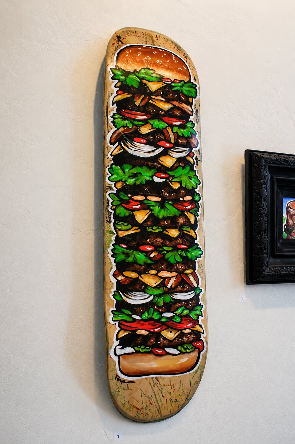 A hand-painted skateboard deck artwork on the gallery wall at VISUAL