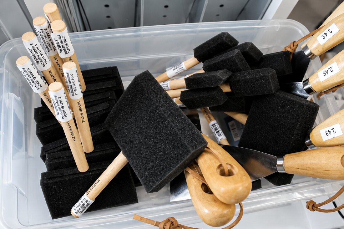 Foam brushes and palette knives in a bin at VISUAL